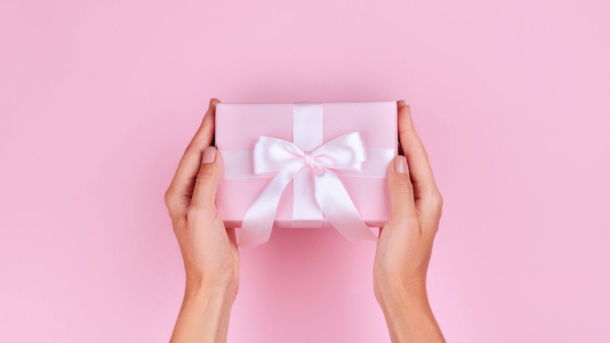 ピンクのギフトボックスを持つ女性の手